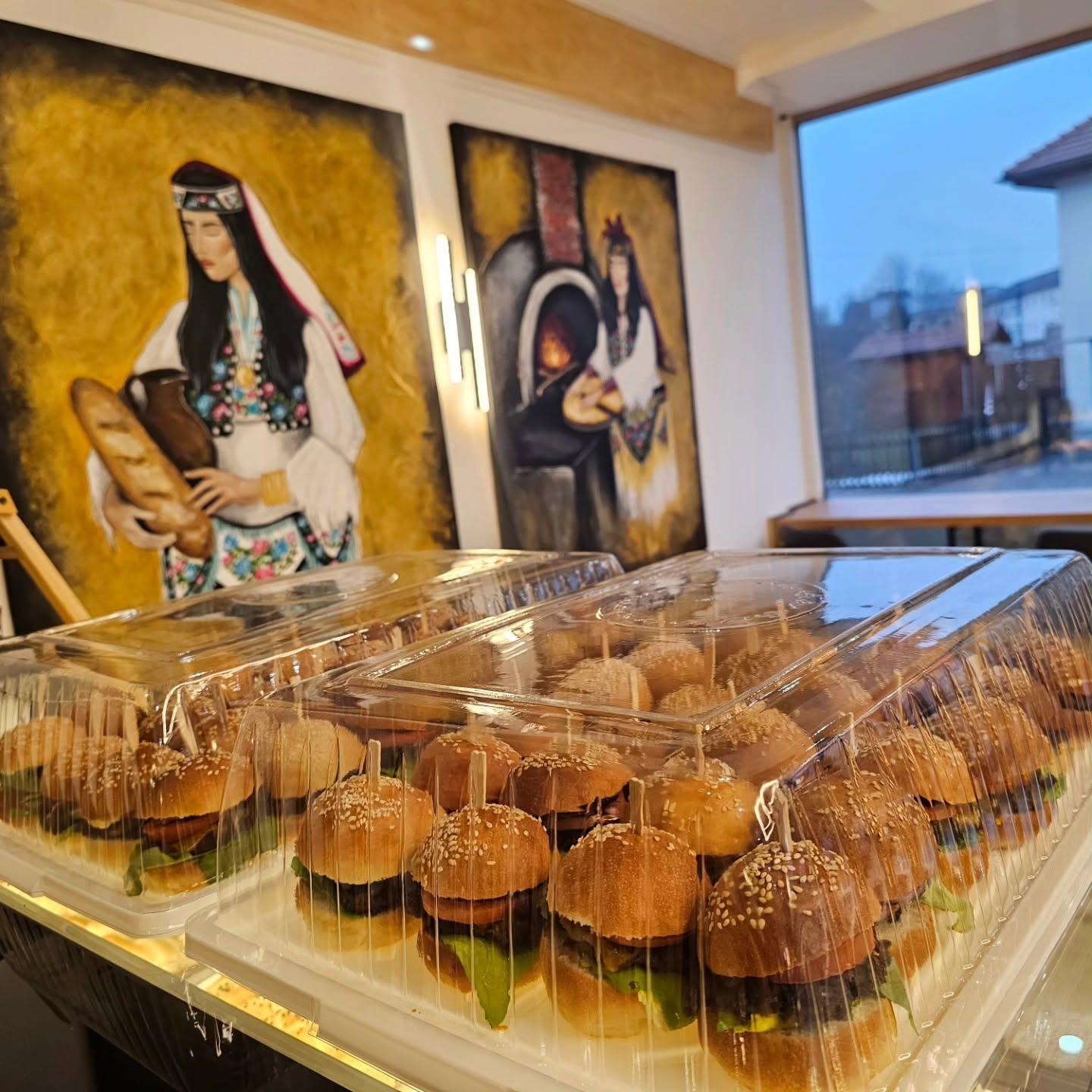 Innenraum der Bäckerei mit goldenen Gemälden und Miniburgern auf der Theke