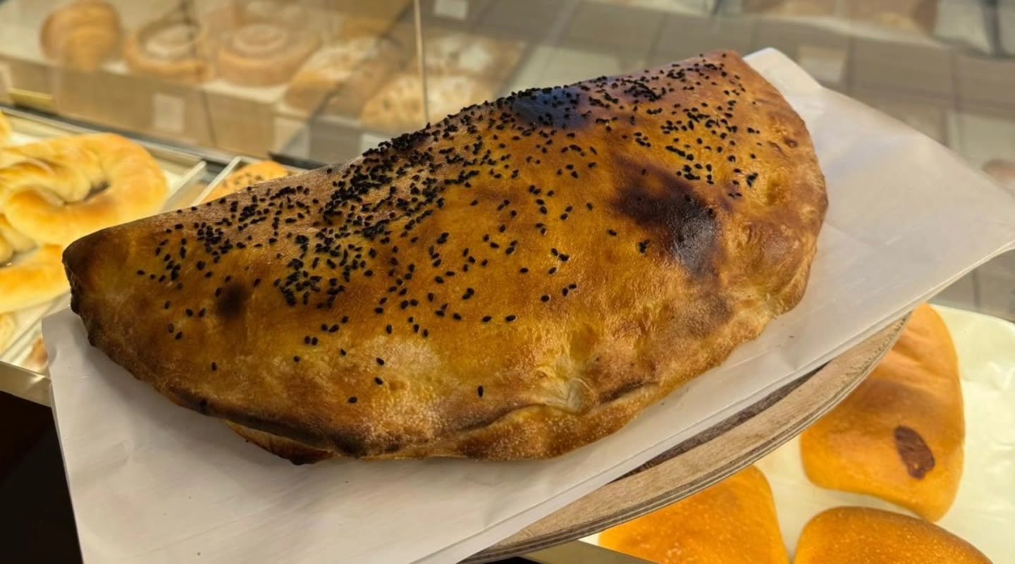 Goldbraunes Samun Calzone mit Schwarzkümmel auf Backpapier